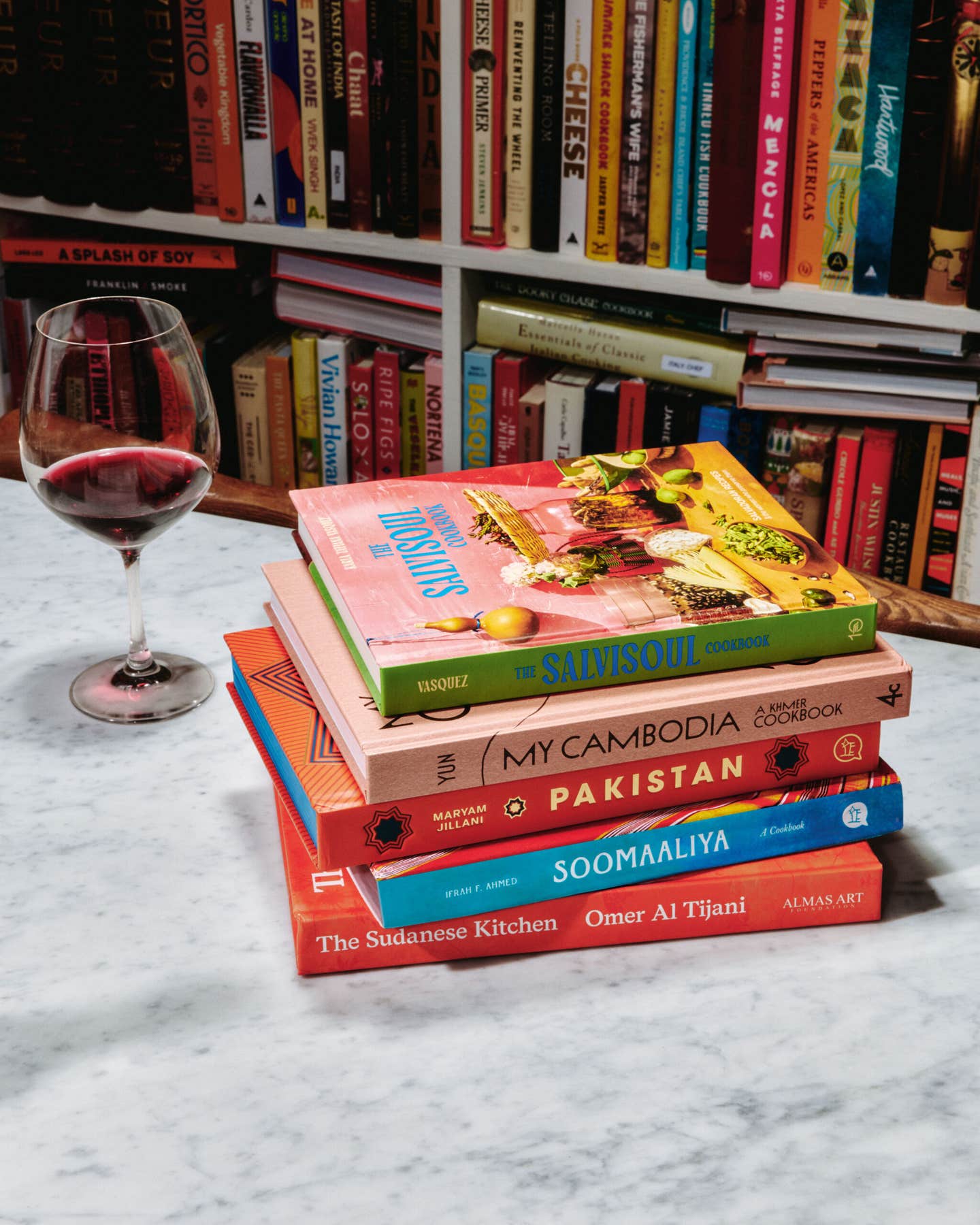 A stack of cookbooks arranged on top of each other, including My Cambodia, Pakistan, SalviSoul, The Sudanese Kitchen, and Soomaaliya.